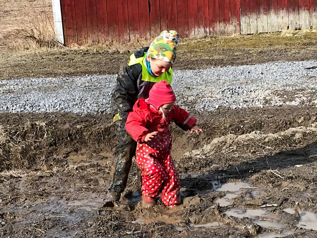 Dagklubbsbarnen Axel och Astrid Nyström hemma på sin eget gård. Storebror hjälper lillasyster.